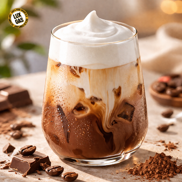 Iced mocha coffee with layered chocolate, milk, and cold foam in a clear glass