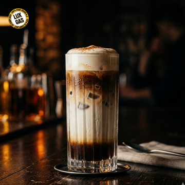 Café con leche español helado con espuma fría y cremosa sobre una capa de café expreso y leche, servido en un vaso de café transparente