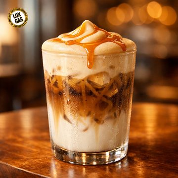 Eis-Latte mit gesalzenem Karamell und goldfarbenem Kalt-Schaum, geschichtet auf Kaffee in einem klaren Café-Glas